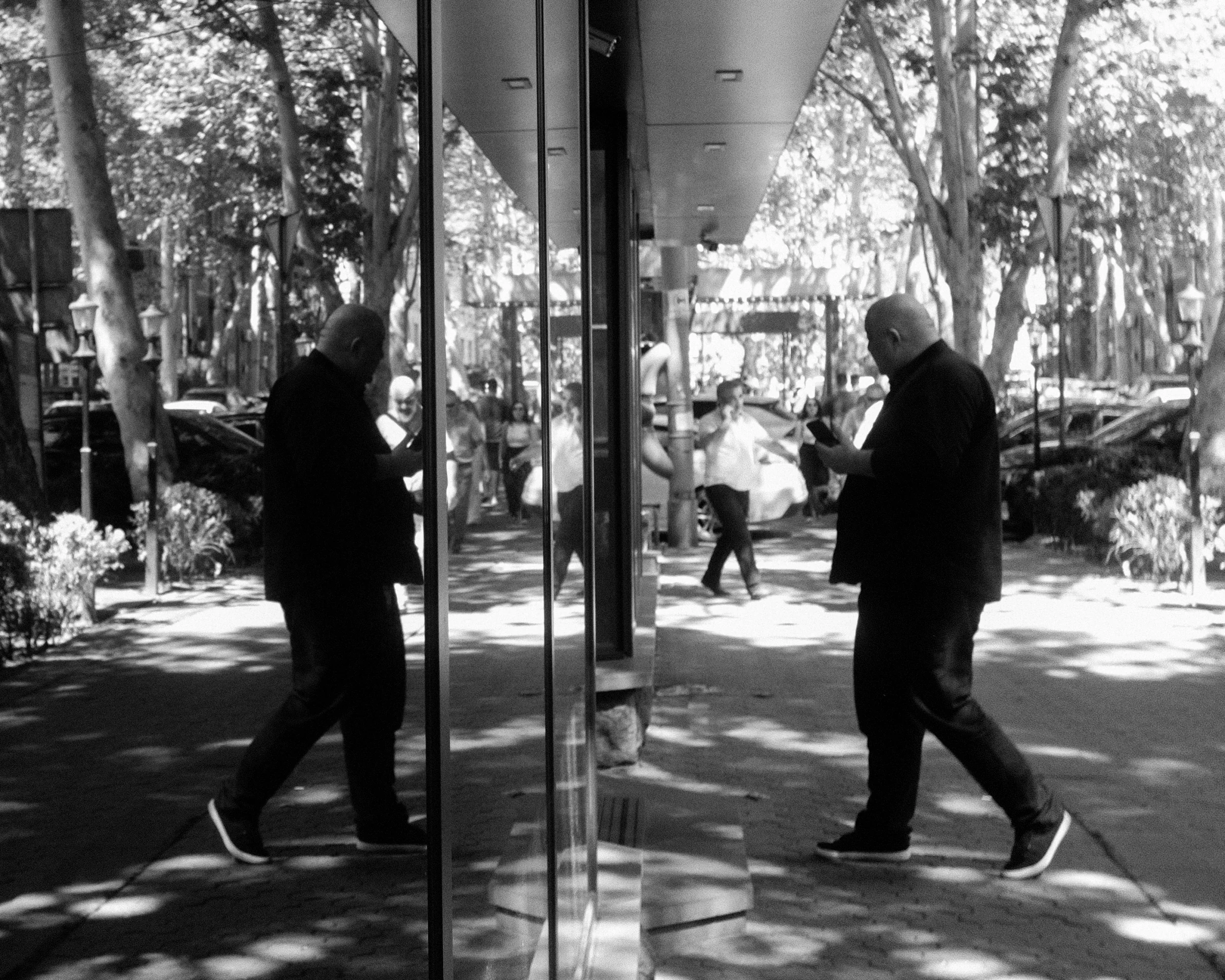 A passerby and his reflection in a glass storefront
